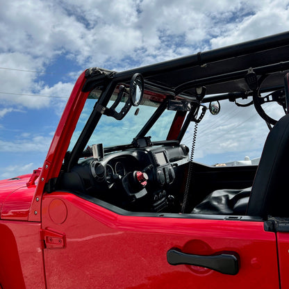 Red off-road vehicle with an open door against a blue sky with clouds
