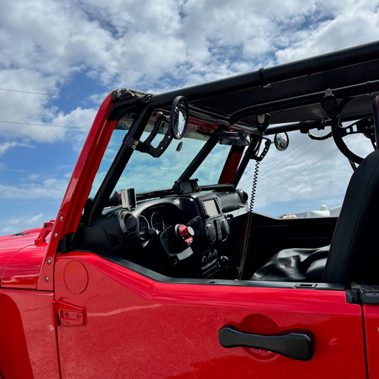Red off-road vehicle with an open door against a blue sky with clouds